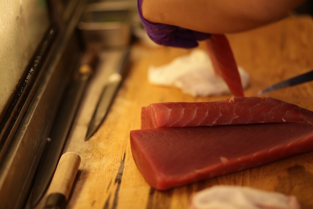 Chef preparing fresh tuna steaks on a wooden board.